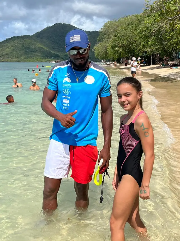 Un entraîneur du FNC et une jeune nageuse dans l'eau, pouce levé avant le départ