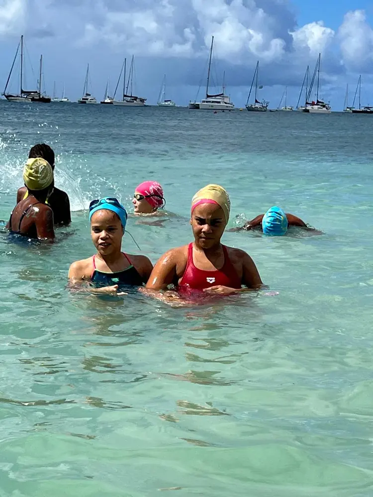 Deux nageuses du FNC dans l'eau pendant l'échauffement, d'autres nageurs derrière elles