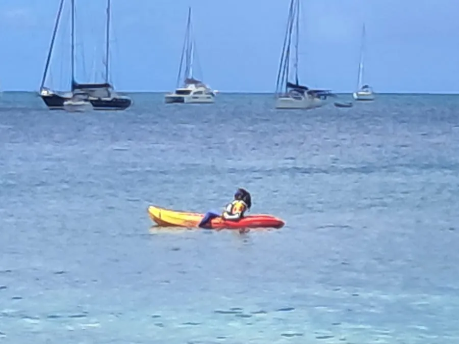 Martine Liancon, présidente du FNC, en kayak sur le parcours pour la sécurité des nageurs, voiliers au mouillage derrière elle