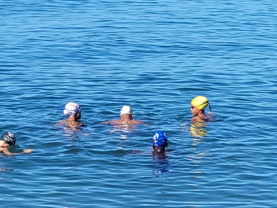 Quelques nageurs en bonnets blancs, jaune et bleu font une pause dans l'eau