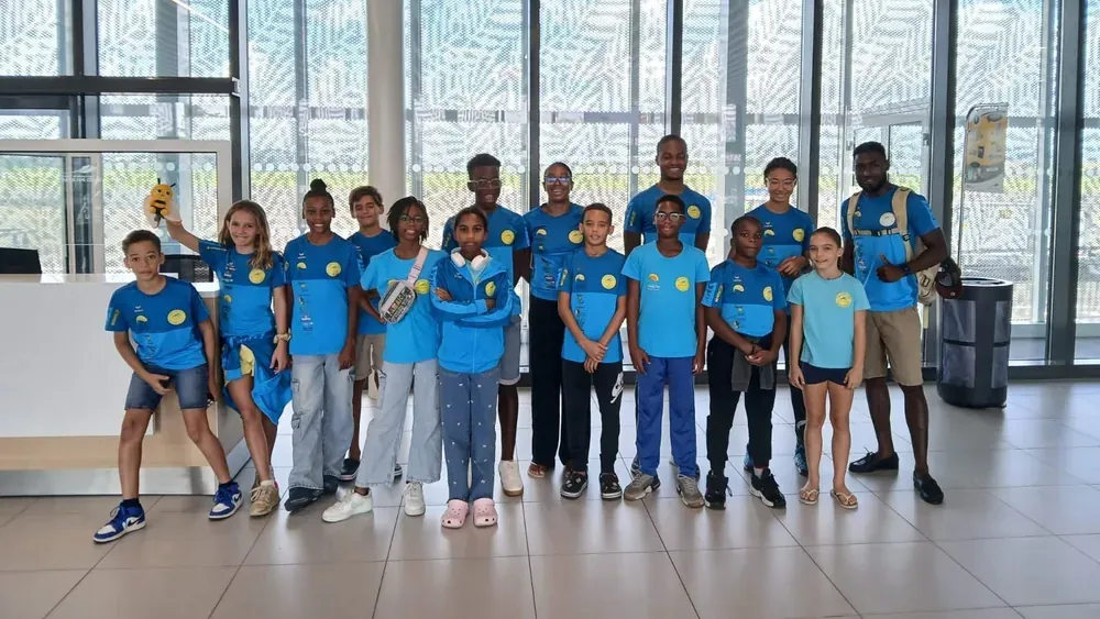 Les jeunes nageurs du François Natation Club en tenue du club, réunis avec leur entraîneur avant un déplacement