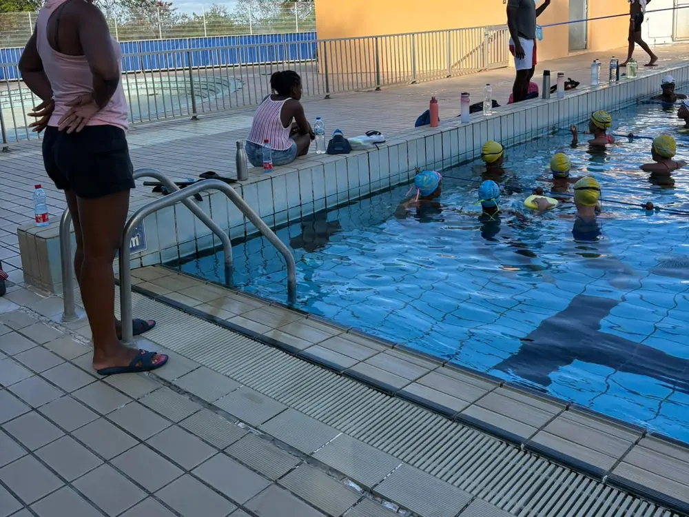 Une encadrante au bord du bassin de la piscine du François pendant que les nageurs travaillent dans l'eau